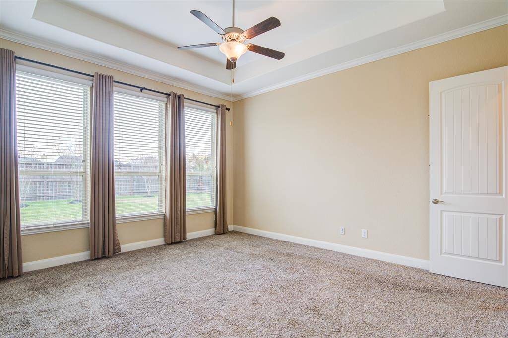 The primary bedroom has a wall of windows, a tray ceiling and crown molding.