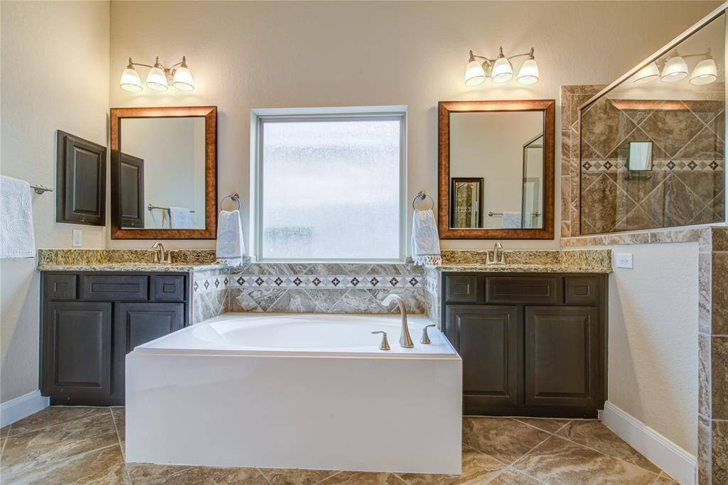 Dual vanities frame the deep soaking tub in the primary bathroom.