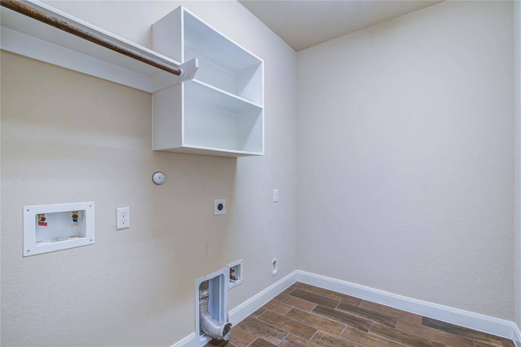 The utility room features and hanging rod and shelf storage. There is space for the washer, dryer and a secondary refrigerator.