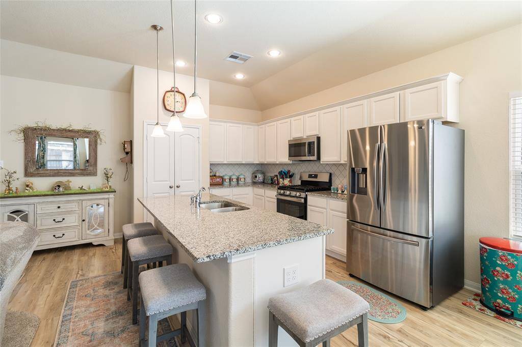 Chef-inspired kitchen featuring granite countertops & an oversized island with breakfast bar seating, perfect for casual dining or gathering with family & friends.