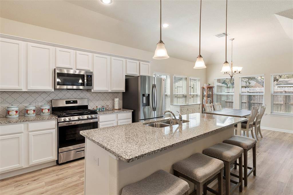Beautifully designed, this kitchen features a striking designer backsplash & upgraded Legacy Plymouth sleek white cabinetry, creating an elegant cooking space perfect for any home chef.