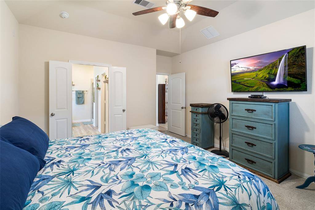 The spacious bedroom features high ceilings & plush carpeting plus an expansive primary ensuite bathroom just beyond the double doors.