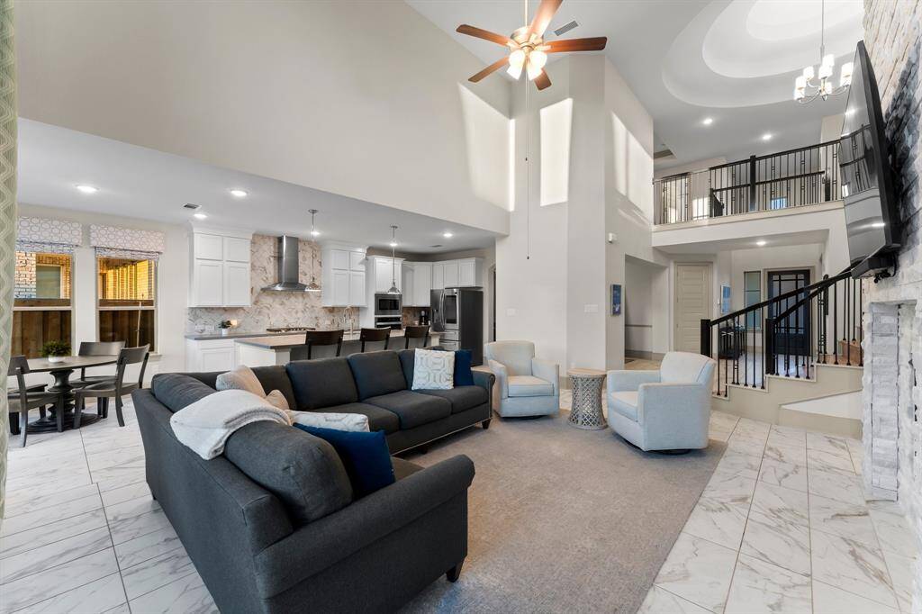Living room flows seamlessly into modern kitchen with white cabinetry and a large island.