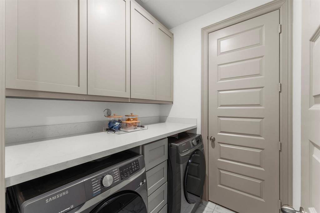 Laundry room off primary closet with added cabinets, a countertop for folding, for a clean and functional space.