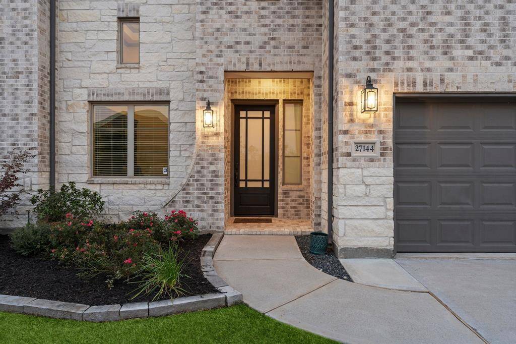 Charming entrance with elegant stonework, warm lighting, and manicured landscaping.