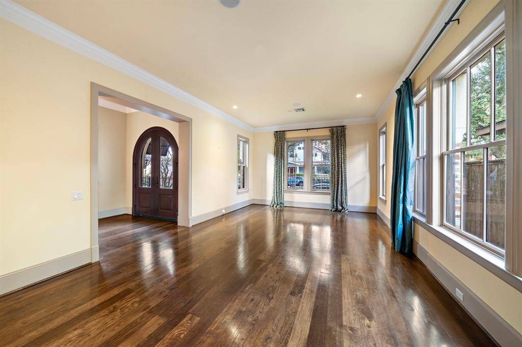 Right off the foyer, find a light-filled dining and sitting area with hardwood floors, timeless finishes, and large windows that frame lush views.