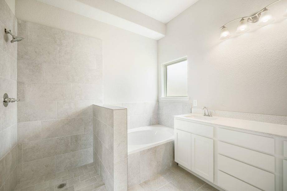 Step into a spa-inspired retreat with this modern primary bath featuring an oversized walk-in shower, soaking tub, and elegant vanity with ample storage. The neutral tile finishes and soft lighting create a serene ambiance, perfect for unwinding at the end of the day.