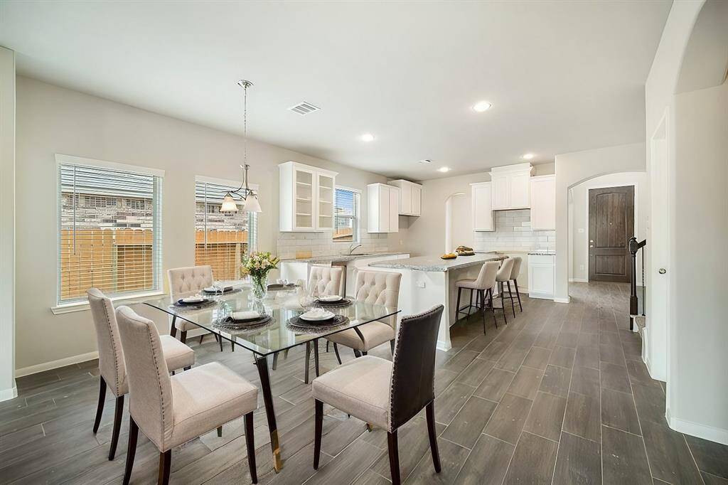 Step into a bright, open-concept kitchen and dining area designed for effortless entertaining. Featuring sleek white cabinetry, a stylish subway tile backsplash, and a large granite island, this kitchen is a chef’s dream. The dining area is surrounded by natural light, creating a warm and inviting space for meals with family and friends.