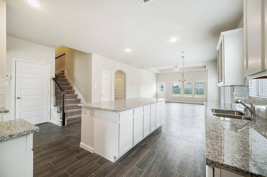 This gourmet kitchen is a showstopper with its massive granite island, ideal for meal prep and entertaining. The sleek white cabinets, stainless steel fixtures, and modern subway tile backsplash create a timeless and sophisticated look. Whether you're hosting or cooking, this space offers both functionality and elegance.