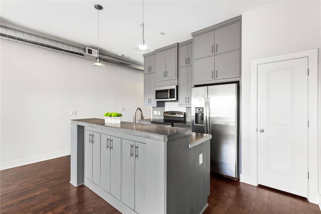 Kitchen designed with casework custom cabinets to the ceiling, offering ample storage.  Featuring stainless steel GE appliances, breakfast bar island with additional storage, and a large pantry (behind door)