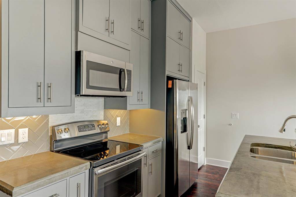 Kitchen boasts elegant subway tile backsplash and concrete countertops