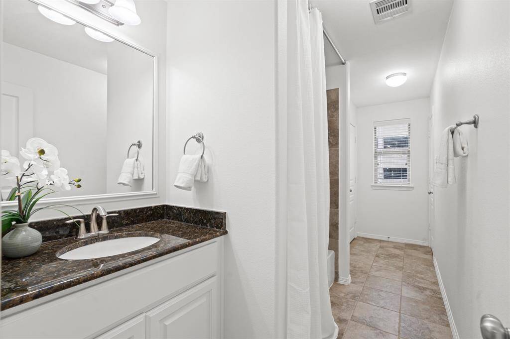 A Thoughtfully Designed Secondary Bath. This shared bathroom connects two bedrooms, offering plenty of space, a sleek granite vanity, and a tub/shower combo—perfect for a smooth morning routine.
