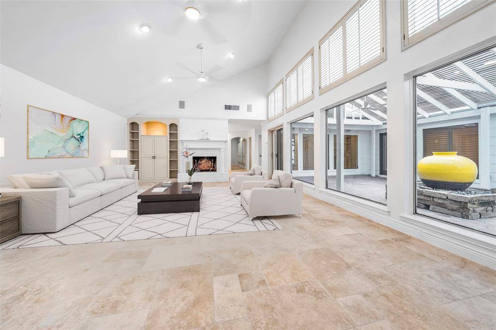 Bathed in natural light from numerous windows, this inviting space offers warmth and charm with a cozy log fireplace, elegantly framed by custom built-ins. (vs)