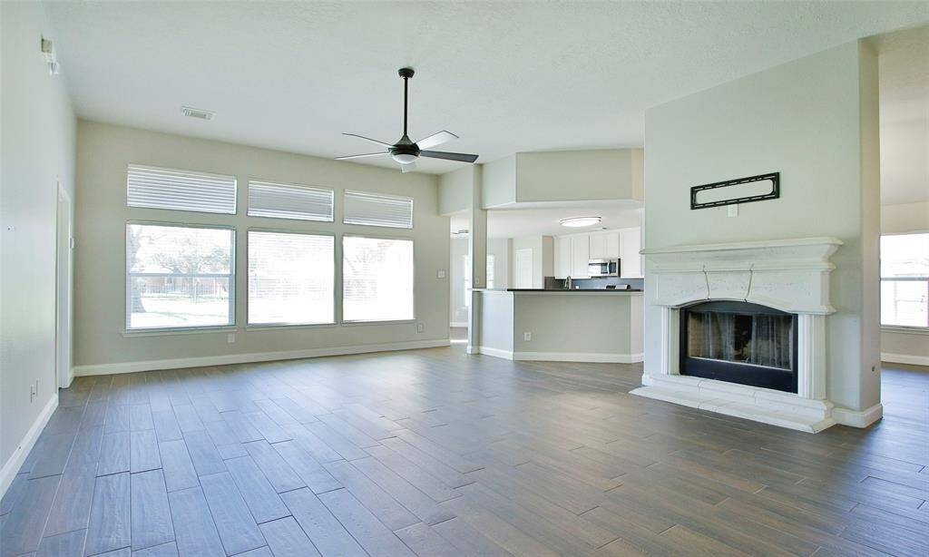 The spacious living room features a gas fireplace with cast stone surround. The kitchen is open to the living with a eat at breakfast bar.