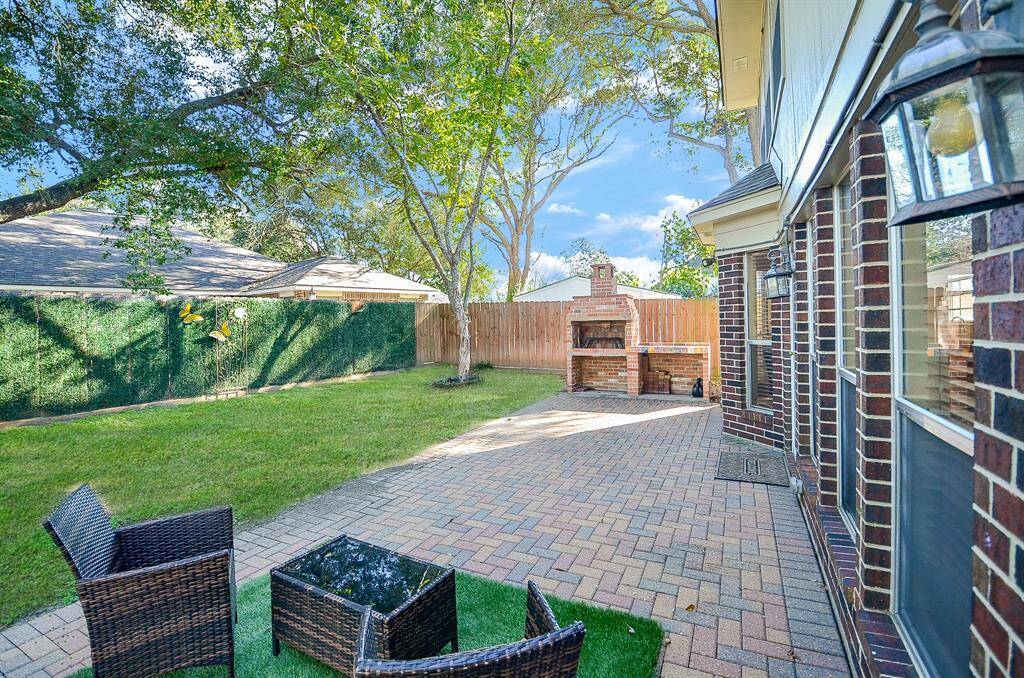 PAVED PATIO W CUSTUM BUILT BRICK GRILL AND BEAUTIFUL FENCE SURROUNDS THE BACKYARD