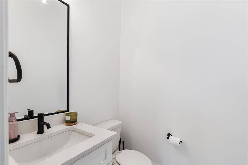The elegant powder room offers a refined aesthetic with a quartz-topped vanity and matte black fixtures. Its modern design ensures a stylish and welcoming space for guests.