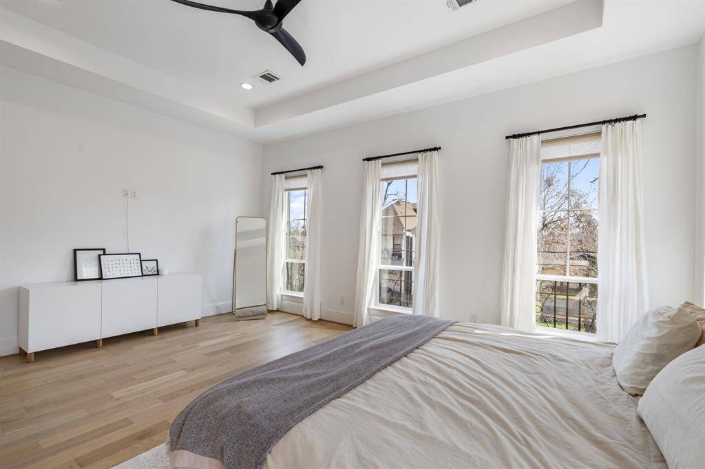 An alternate angle highlights the room’s generous size, elegant hardwood floors, and abundant natural light. The large windows showcase picturesque neighborhood surroundings, adding charm and tranquility.