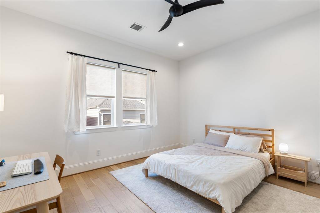 Bright and welcoming, this secondary bedroom features wide plank wood flooring and large windows. Perfect for guests, family, or creative use, with convenient access to a full bath.