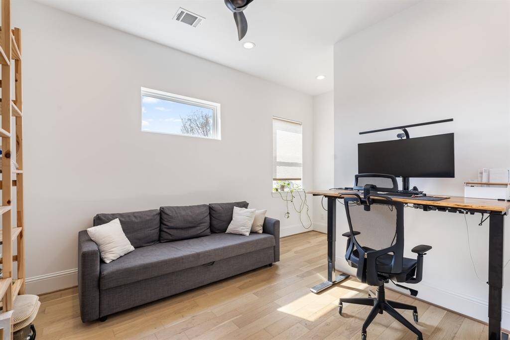 A well-lit office with natural wood floors and a flexible layout for various workspace needs. Large windows allow in abundant natural light, creating an inspiring home office environment.
