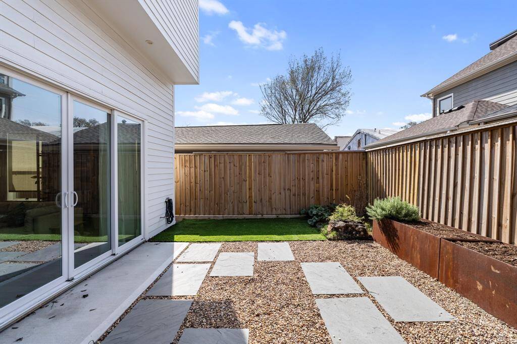 Another angle of the backyard, showcasing the sliding glass doors that seamlessly connect indoor and outdoor living. The fenced yard offers privacy and charm for enjoying sunny afternoons.