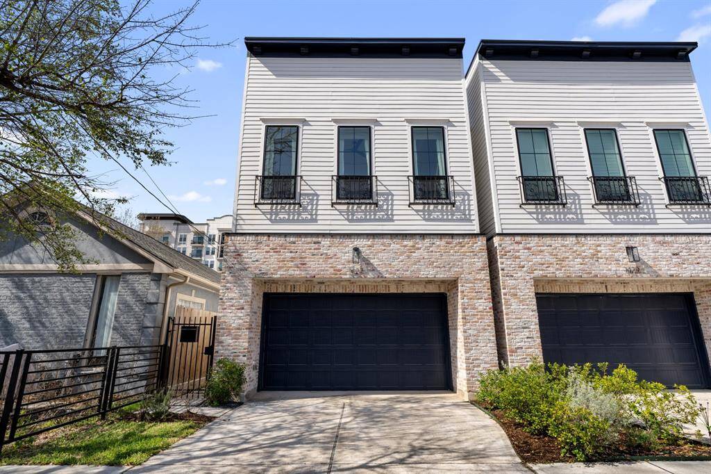 A striking front façade with timeless brick accents and elegant balconies. The double-wide driveway leads to an attached two-car garage, combining style and convenience.