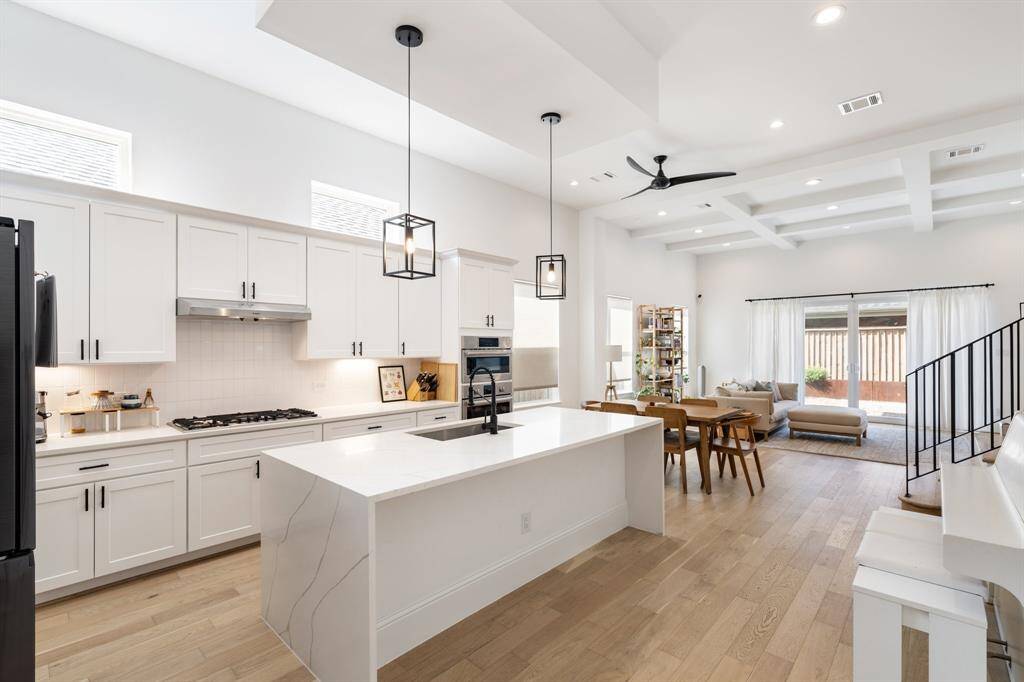 The bright and airy kitchen showcases crisp white cabinetry, a spacious walk-in pantry, and modern pendant lighting. Its thoughtful design balances function and elegance for everyday living.