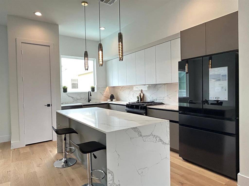 This elegant kitchen features sophisticated European-style cabinets with sleek, minimalist lines paired with stunning quartz countertops for a modern luxury and timeless appeal.