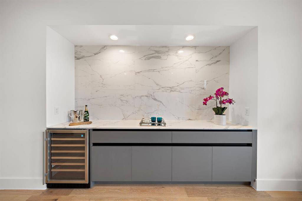 This sleek dry bar adds both style and function to the modern home. Featuring polished cabinetry, a wine cooler, and ample storage for glassware and spirits, it's the ideal space for entertaining or enjoying a quiet drink.