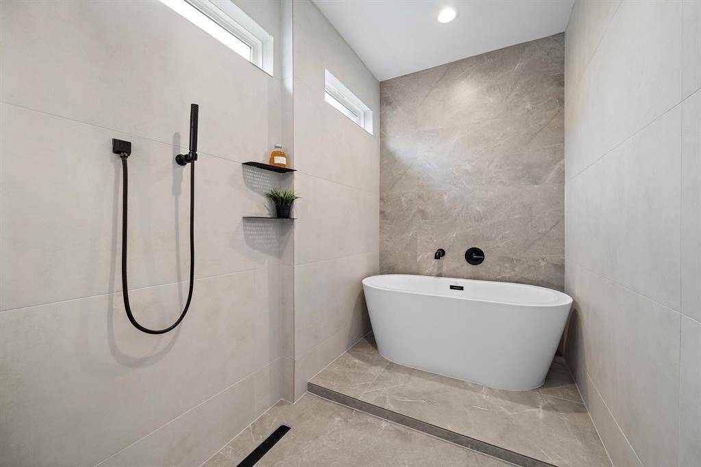 Indulge in luxury with this spa-inspired bathroom featuring a central freestanding bathtub the tile tones add to the serene ambiance, creating the perfect retreat for relaxation and rejuvenation.