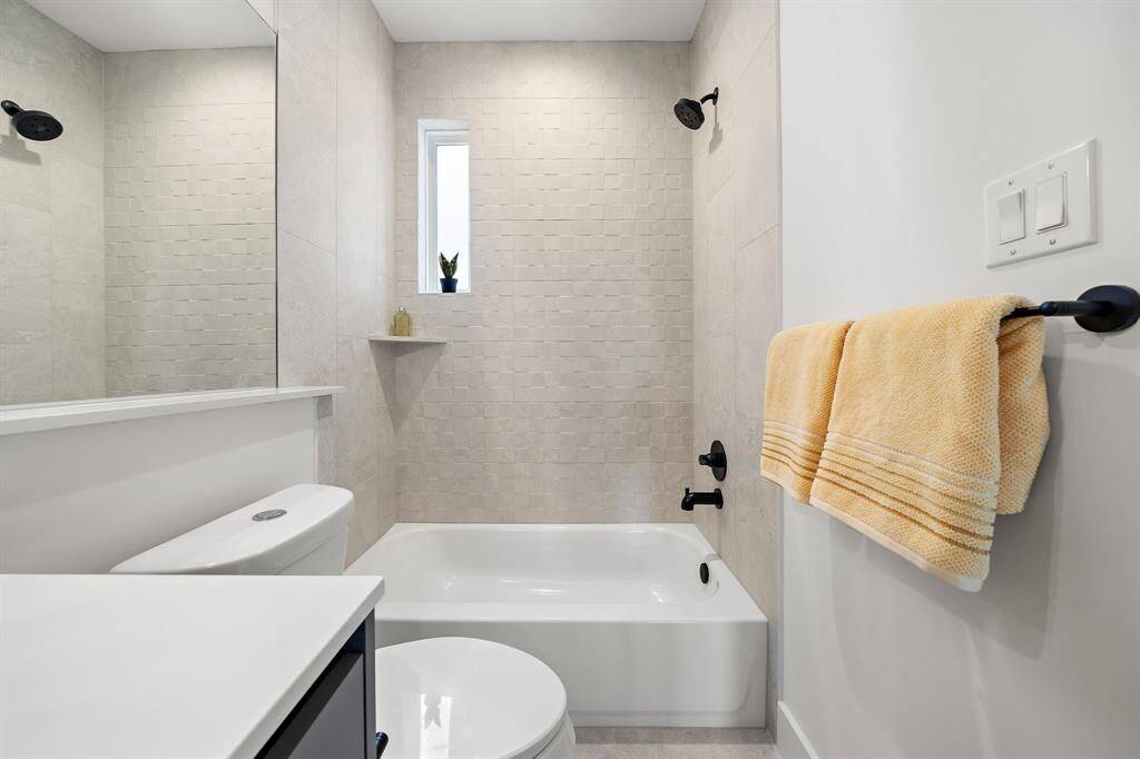 This secondary bathroom on the third floor features modern fixtures, a sleek vanity, and a shower-tub combo.