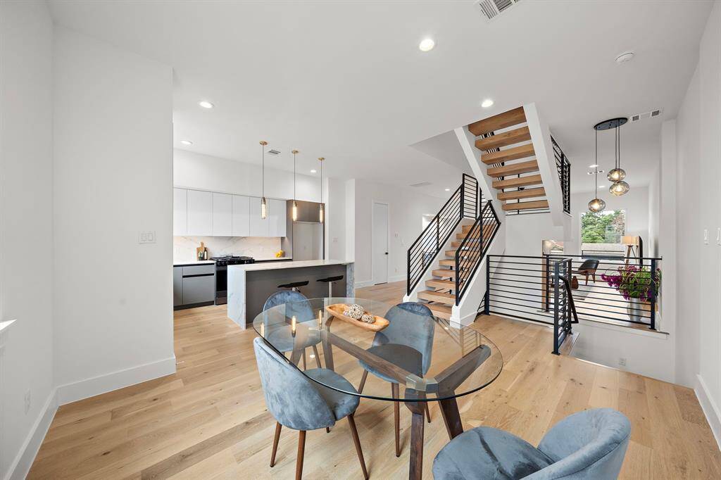 Bright and modern open-concept kitchen and dining area with light wood flooring, sleek cabinetry, and pendant lighting. Features a spacious island with seating.