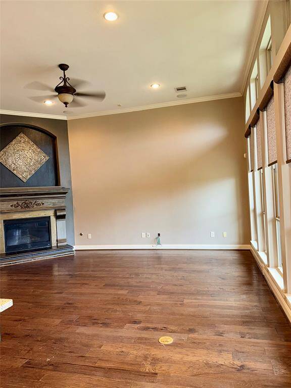 This spacious living area features hardwood floors, a decorative fireplace, and large arched windows that provide abundant natural light. The open layout flows into the kitchen creating an inviting space perfect for entertaining or relaxing.
