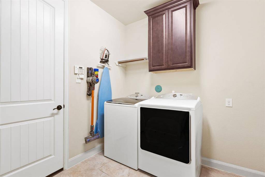 This expansive laundry room is designed for efficiency and convenience, featuring plenty of storage cabinets, and room for both a washer and dryer.