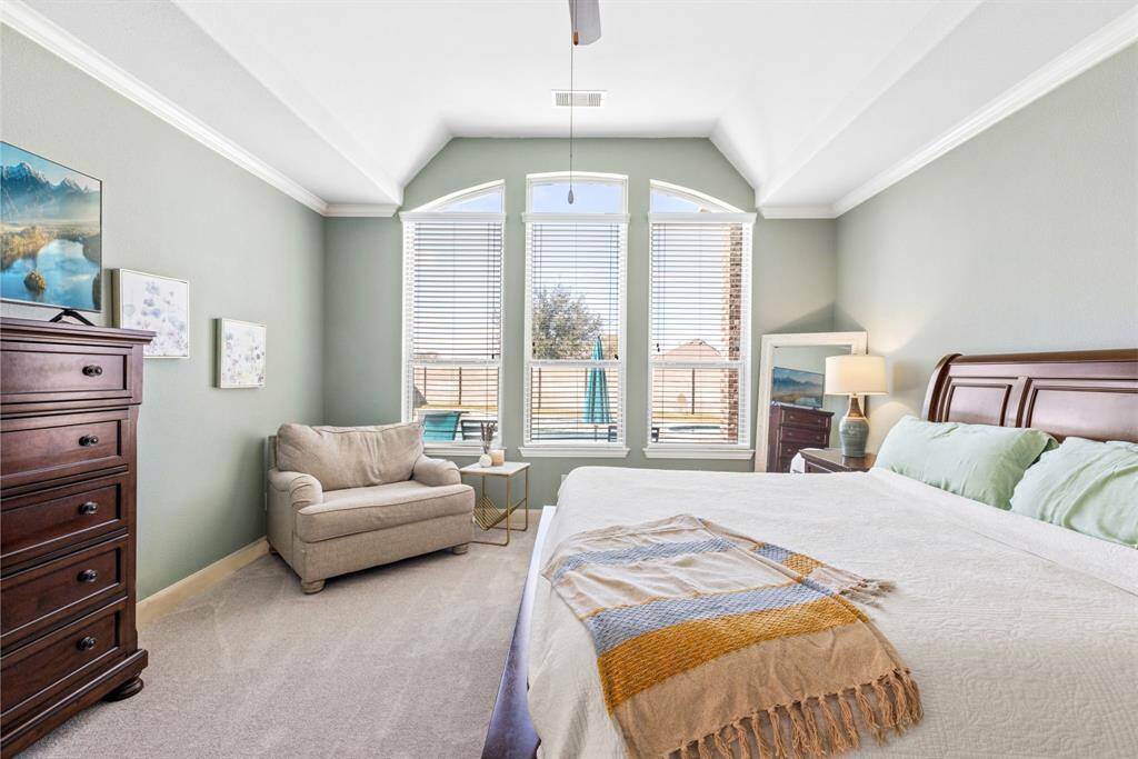 Spacious & Serene Primary Suite – Retreat to this expansive primary bedroom, featuring tall windows that fill the space with natural light and create a warm, inviting atmosphere.
