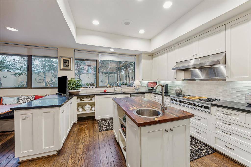 KITCHEN-Light and bright updated kitchen with honed granite countertops, porcelain backsplash, DACOR 4 burner range with Thermador vent hood and grill as well a a butcher block island with hammered metal beverage/veggie sink.