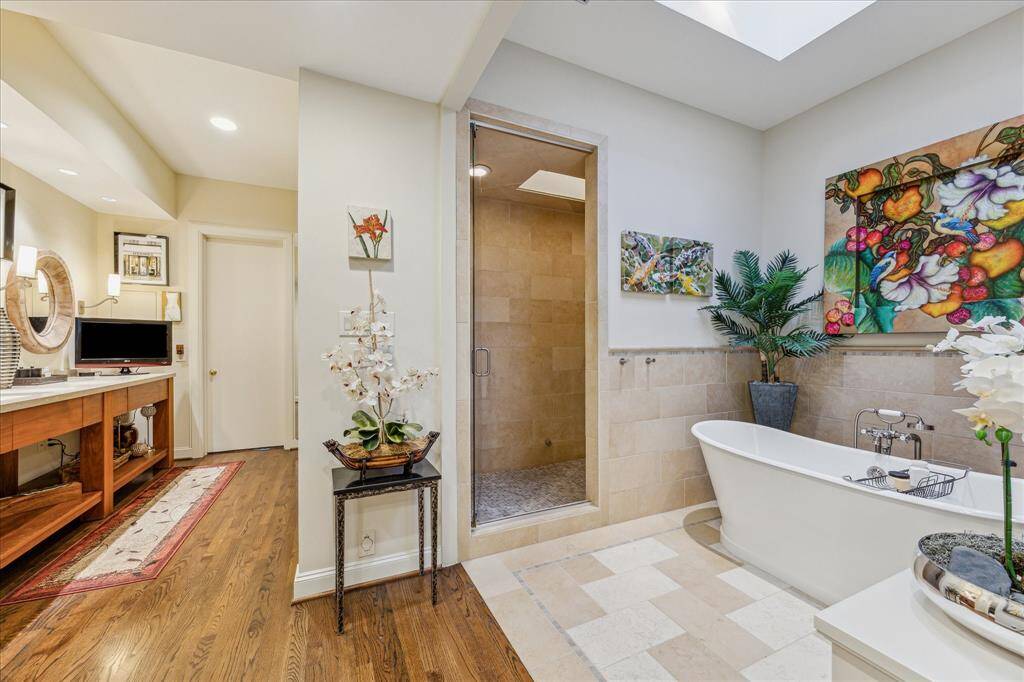 PRIMARY BATHROOM III-This serene space features a freestanding soaking tub as well as a walk-in shower with glass door, bench, stone surround and body sprayer.