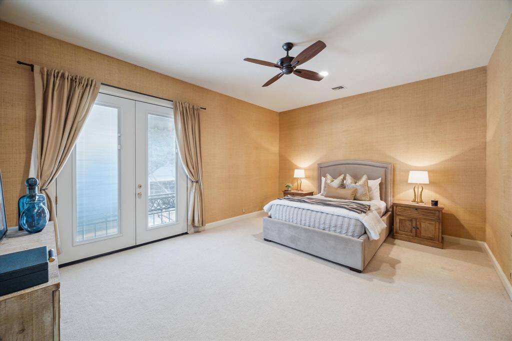 SECONDARY BEDROOM-Spacious bedroom featuring a Juliet balcony, en-suite bath, grass cloth walls, new fan and walk-in closet with built-ins.