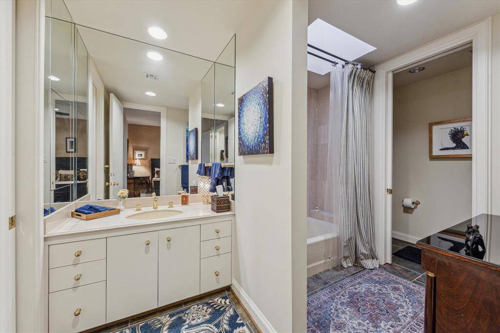 SECONDARY BATHROOM-This bathroom features a marble countertop and tub/shower with tile surround.