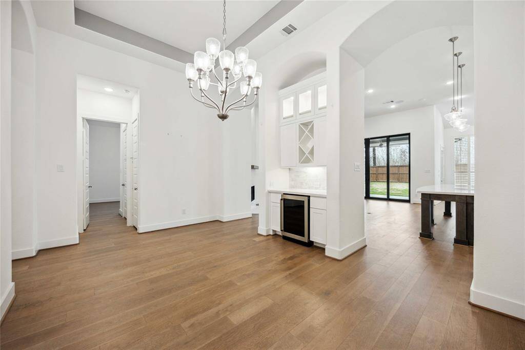 View of formal dining room with wine fridge. Kitchen and hall to secondary bedrooms in the background.