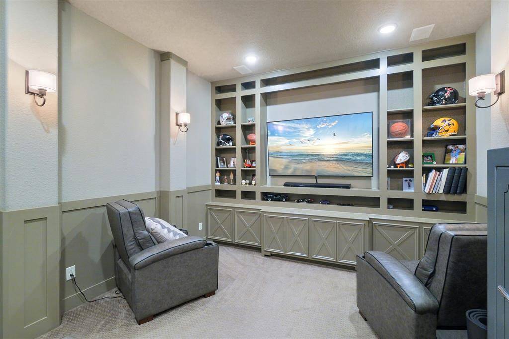 This cozy home theater features built-in shelving around a large flat-screen TV, comfortable custom made leather seating, and soft wall lighting, creating an intimate entertainment space.