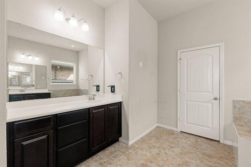 This primary bathroom is definitely move-in ready! Featuring a spa like walk-in shower with tile surround, separate garden tub for soaking after a long day with custom tile detailing, dark stained cabinets with light countertops, spacious walk-in closet with shelving, high ceilings, neutral paint, sleek and modern finishes.
