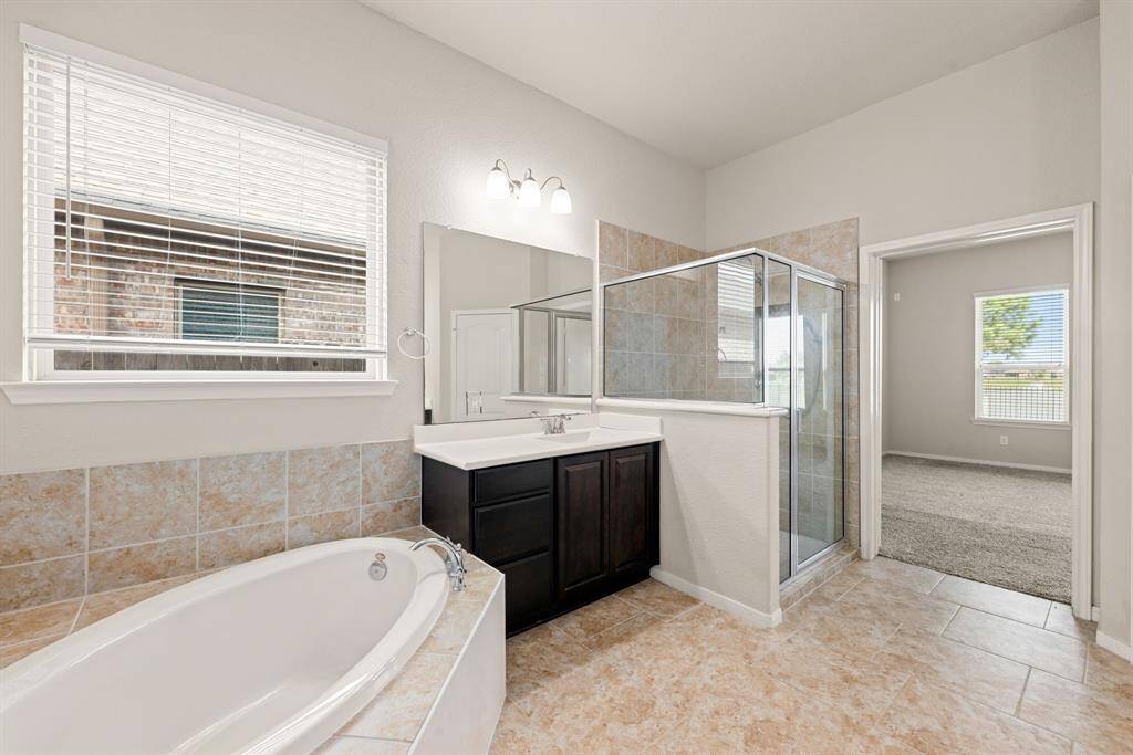 This additional view of the primary bath showcases an oversized walk-in shower with tile surround and a separate garden tub perfect for soaking after a long day.