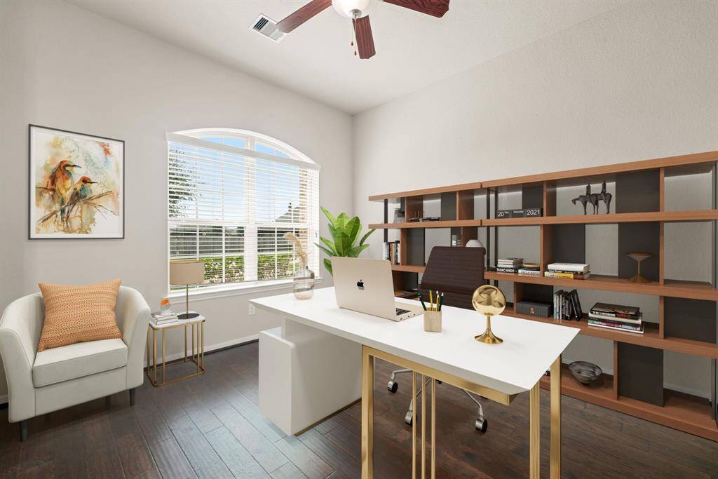 Quietly nestled in front of the home is the handsome home office. Featuring rich wood floors, high ceilings, large arched window with privacy blinds and neutral paint.