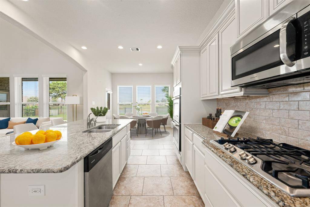 This kitchen is by far any chef’s dream! This spacious kitchen features large windows, high ceilings, bright white cabinets, granite countertops, SS appliances, modern tile backsplash, recessed lighting, extended counter space, granite kitchen island with double sink and space for breakfast bar and a walk-in pantry all overlooking your huge family room.