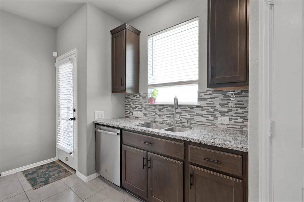 This kitchen features modern cabinetry with sleek backsplash & granite countertops