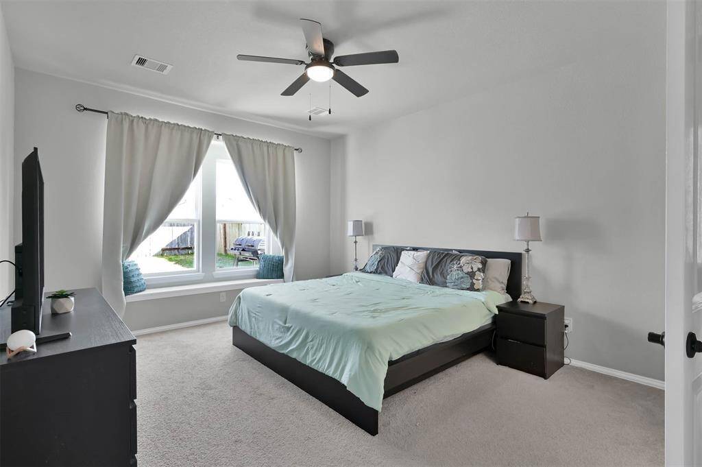 Primary bedroom located on the first floor features a large windows, allowing natural light to brighten the space