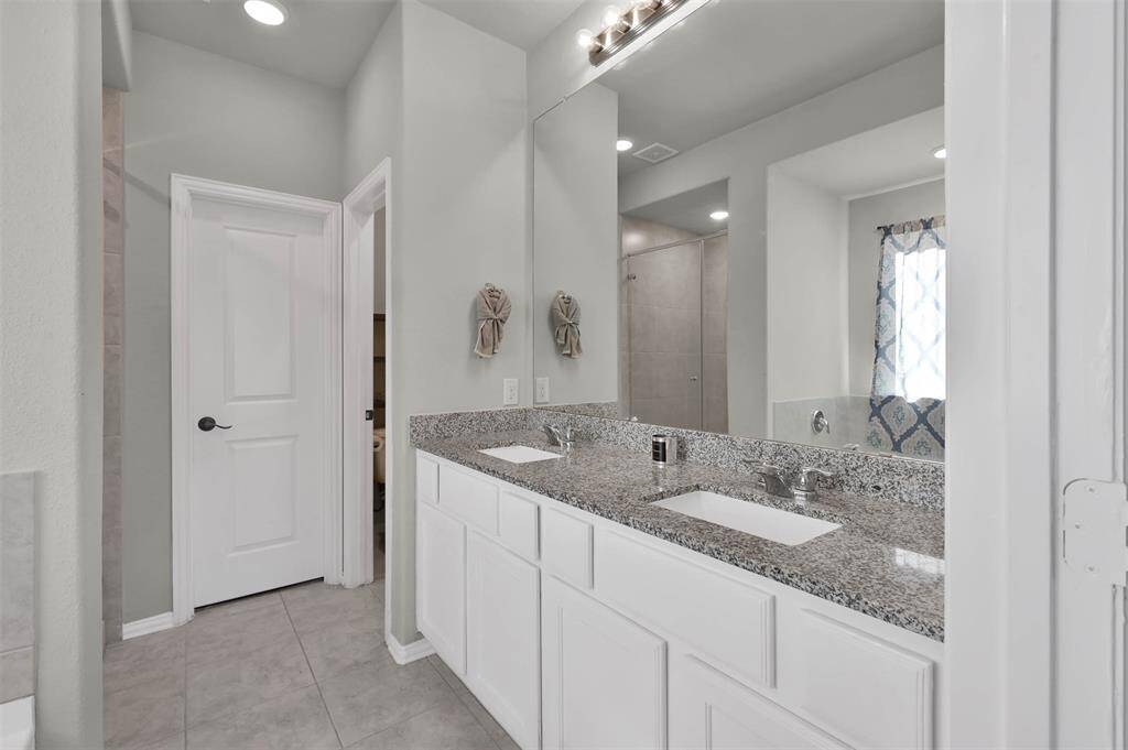 Ample lighting, a large mirror, and a tiled shower area, create a bright & inviting space