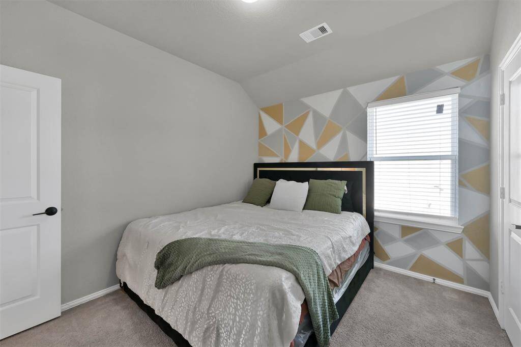 Upstairs guest BR #2 - cozy bedroom with a modern geometric accent wall, carpeted flooring, and ample natural light
