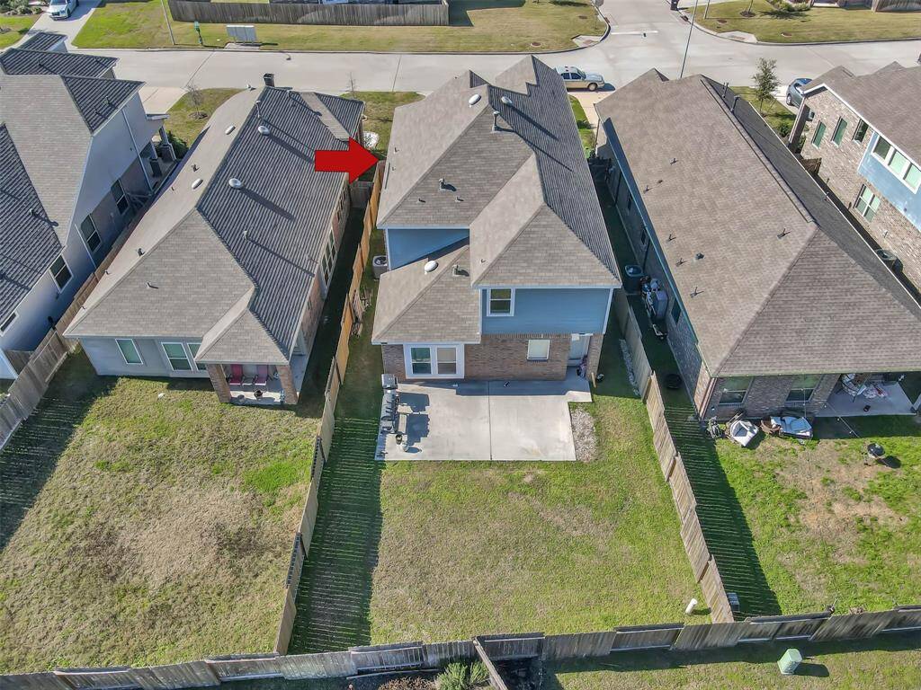 This aerial view showcases a fenced backyard & patio area with lush green backyard with plenty of space