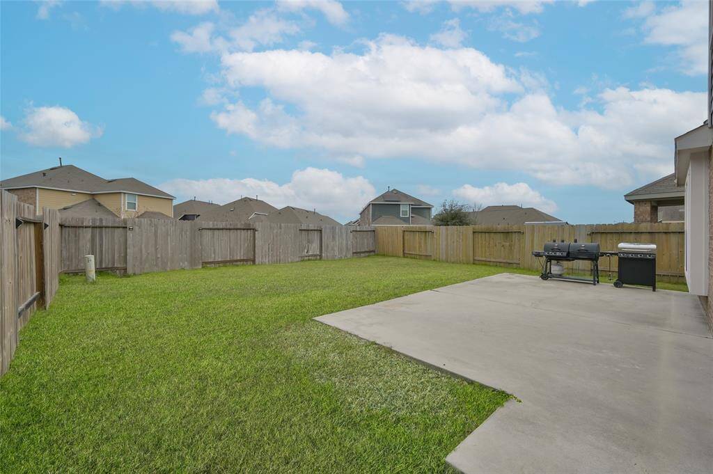 Spacious fenced backyard with a concrete patio, ideal for outdoor gatherings & barbecues